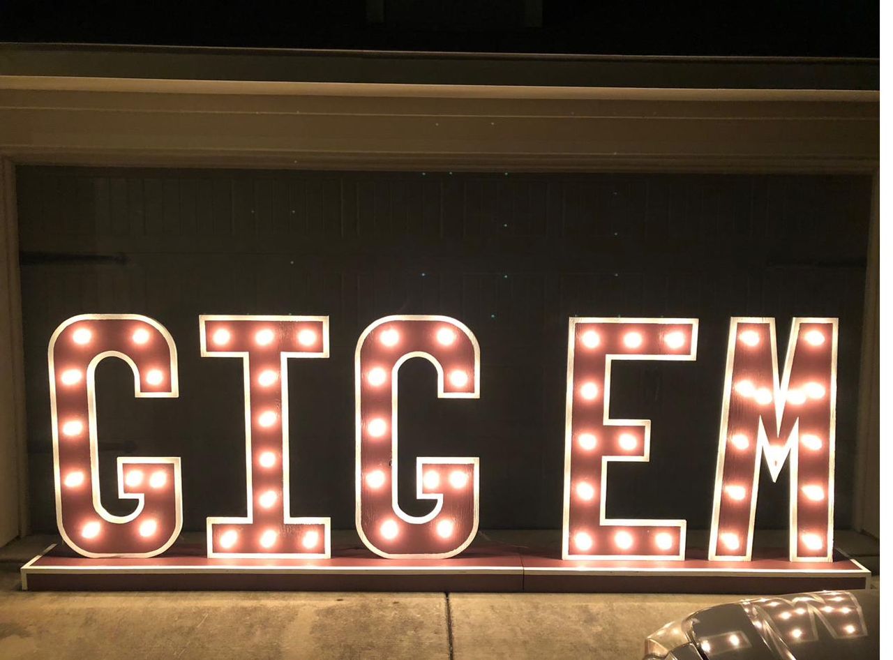 Glowing GIG 'EM marquee letters lit up at night