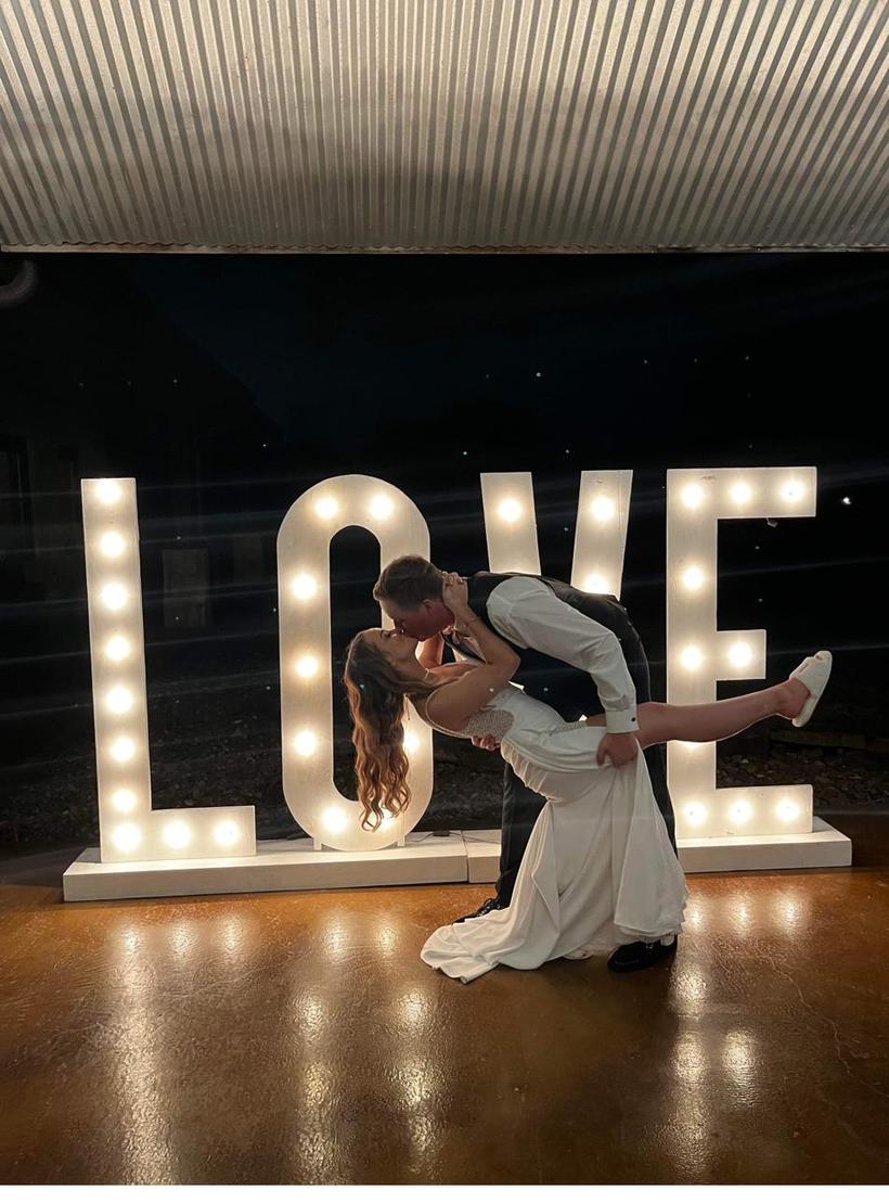 LOVE marquee letters lit up behind a wedding couple